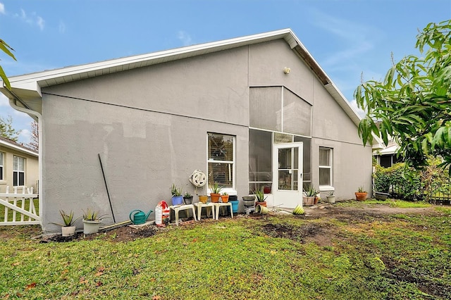 back of property featuring stucco siding, fence, and a yard