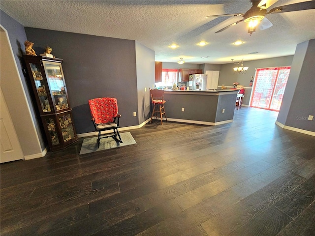 living area featuring ceiling fan with notable chandelier, dark hardwood / wood-style floors, and a textured ceiling