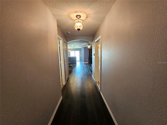 hallway with dark wood-type flooring and a textured ceiling