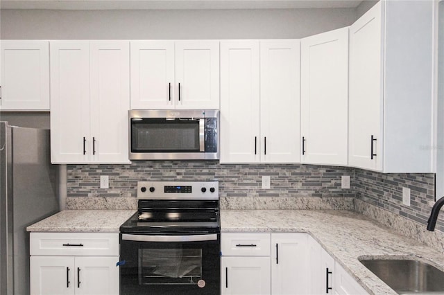 kitchen featuring stainless steel appliances, white cabinetry, sink, and tasteful backsplash