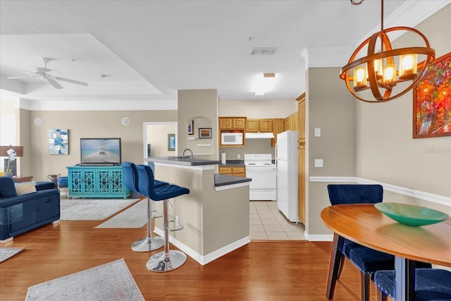 kitchen featuring sink, hanging light fixtures, white appliances, kitchen peninsula, and light wood-type flooring