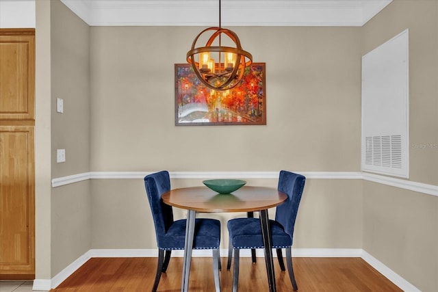 dining room featuring ornamental molding, light wood-type flooring, and an inviting chandelier