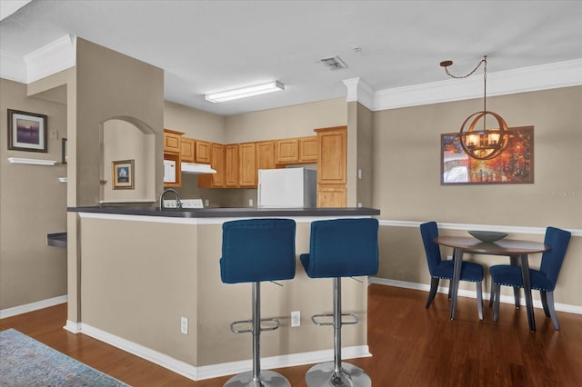 kitchen with light brown cabinetry, sink, a breakfast bar area, white refrigerator, and dark hardwood / wood-style flooring