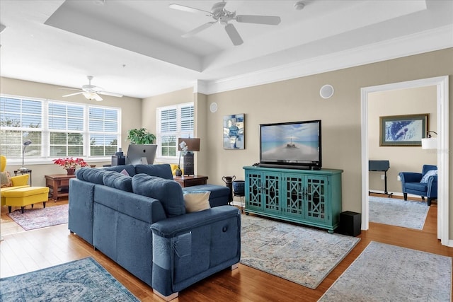 living room with ceiling fan, a raised ceiling, and hardwood / wood-style floors