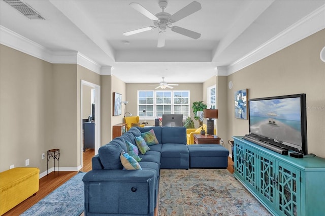 living room featuring hardwood / wood-style floors, crown molding, a raised ceiling, and ceiling fan