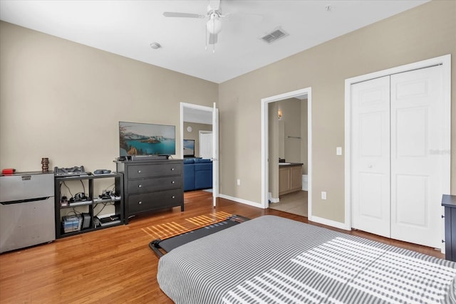 bedroom with wood-type flooring, connected bathroom, ceiling fan, and a closet