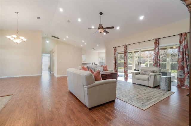 living room with ceiling fan with notable chandelier, hardwood / wood-style floors, and high vaulted ceiling