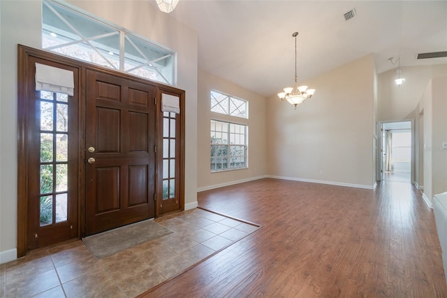 foyer entrance featuring a notable chandelier, wood-type flooring, and high vaulted ceiling