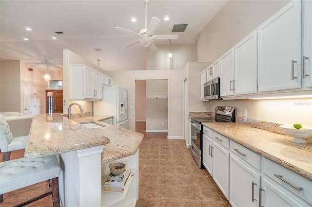 kitchen with sink, a breakfast bar area, white cabinets, hanging light fixtures, and stainless steel appliances