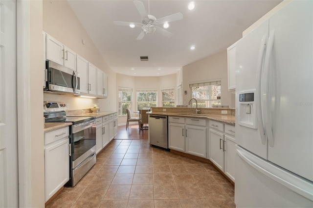 kitchen with sink, light tile patterned floors, white cabinetry, stainless steel appliances, and light stone counters