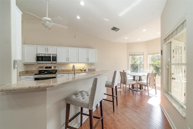 kitchen featuring light stone counters, stainless steel appliances, light hardwood / wood-style flooring, and white cabinets