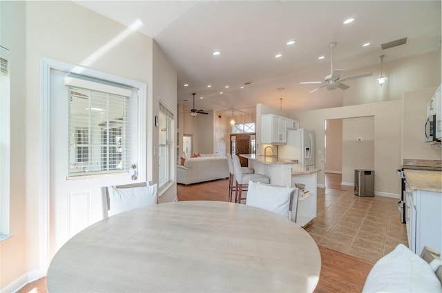 dining space featuring light tile patterned floors, vaulted ceiling, sink, and ceiling fan