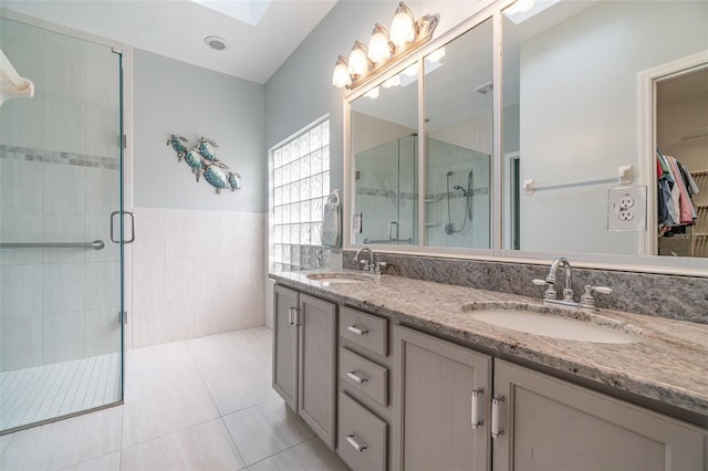 bathroom with walk in shower, vanity, tile patterned flooring, and tile walls