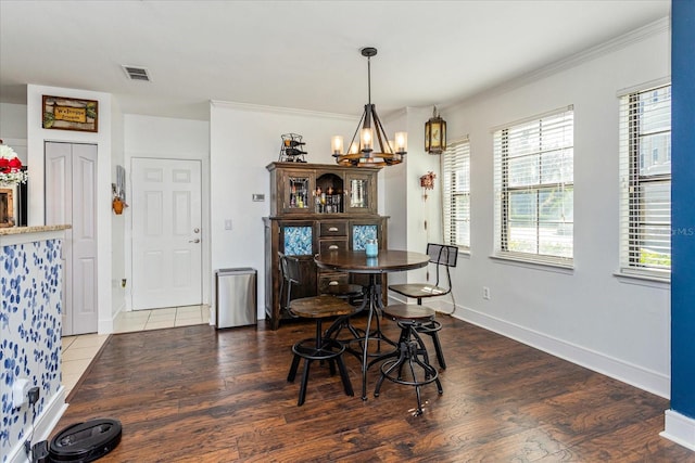 dining space with hardwood / wood-style flooring, ornamental molding, and a chandelier