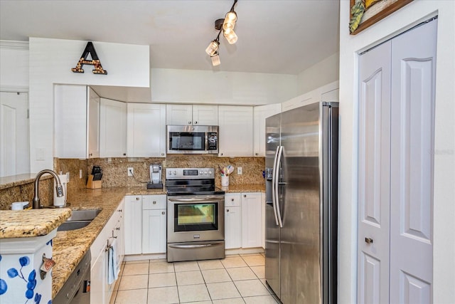 kitchen with white cabinetry, sink, backsplash, stainless steel appliances, and light stone countertops