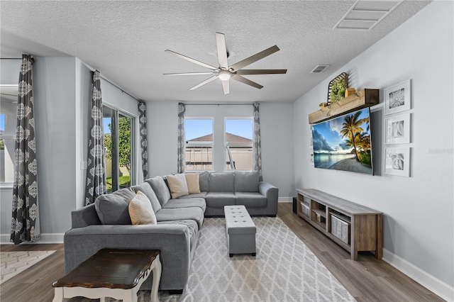 living room featuring ceiling fan, wood-type flooring, and a textured ceiling