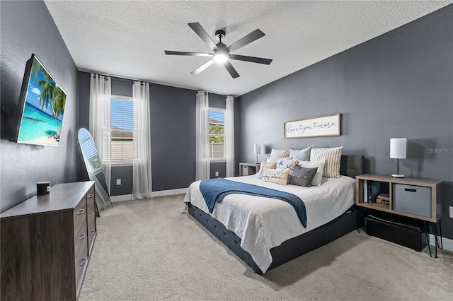 bedroom featuring ceiling fan, light carpet, and a textured ceiling