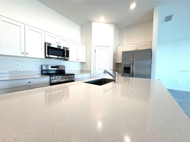 kitchen featuring white cabinetry, appliances with stainless steel finishes, light stone countertops, and sink