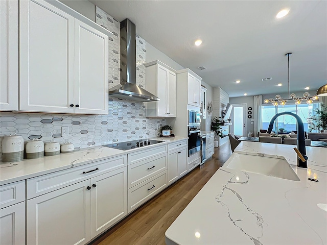 kitchen with appliances with stainless steel finishes, tasteful backsplash, white cabinetry, sink, and wall chimney range hood