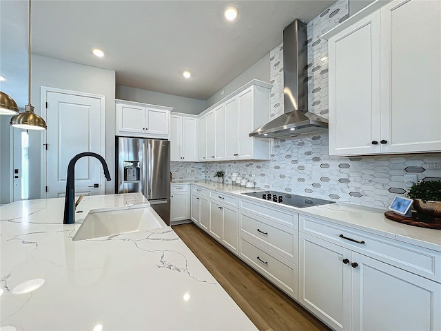 kitchen with wall chimney exhaust hood, white cabinetry, stainless steel fridge with ice dispenser, black electric cooktop, and pendant lighting