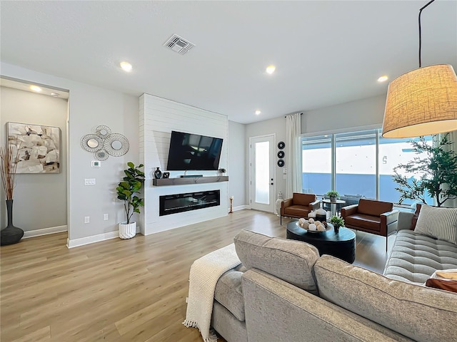 living room with a large fireplace and light hardwood / wood-style flooring