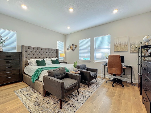 bedroom featuring multiple windows, a textured ceiling, and light wood-type flooring