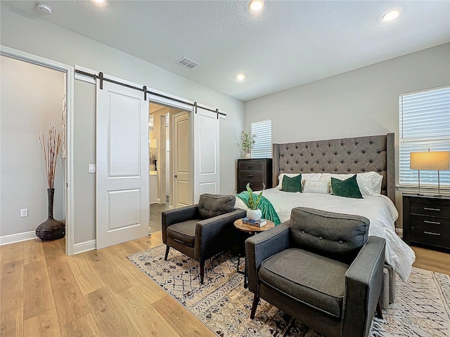 bedroom featuring a barn door and light hardwood / wood-style flooring