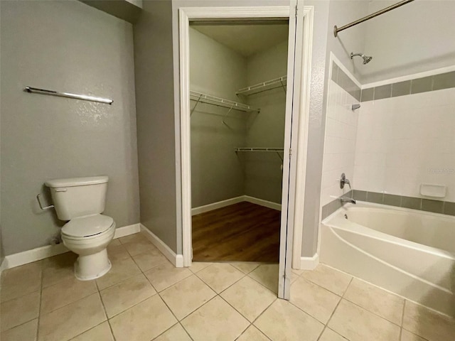 bathroom with tile patterned flooring, tiled shower / bath, and toilet