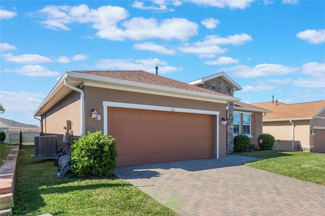 ranch-style home featuring a garage, central AC unit, and a front yard