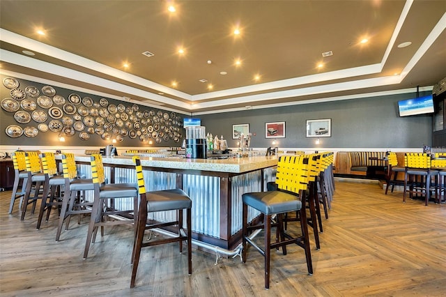 bar with parquet flooring and a tray ceiling