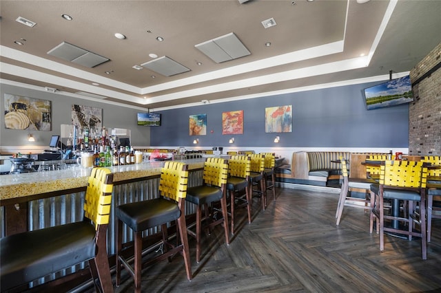 interior space with dark parquet floors and a tray ceiling