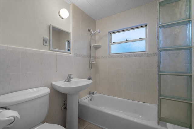 bathroom featuring toilet, tiled shower / bath combo, tile patterned flooring, and tile walls