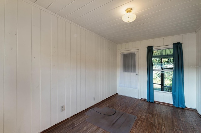 spare room with dark wood-type flooring and wood walls