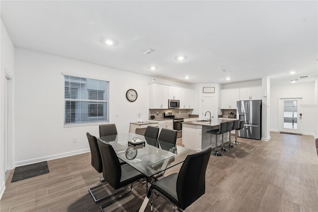 dining area with sink and light hardwood / wood-style floors