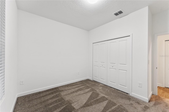 unfurnished bedroom featuring carpet floors, a closet, and a textured ceiling