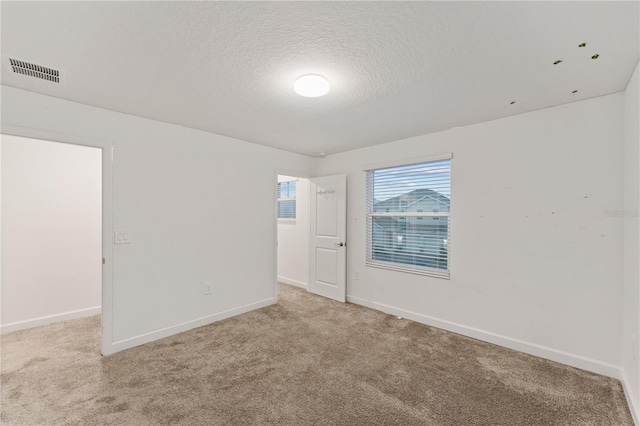 carpeted empty room with a textured ceiling