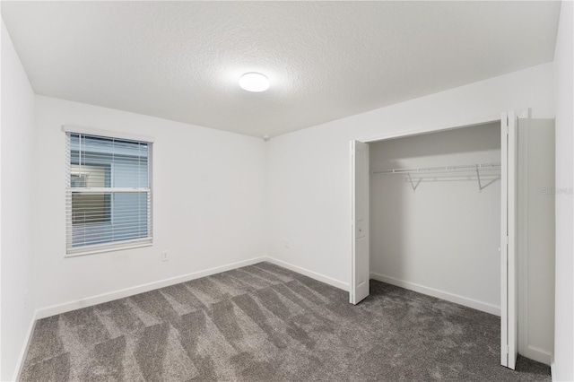 unfurnished bedroom featuring dark colored carpet, a textured ceiling, and a closet