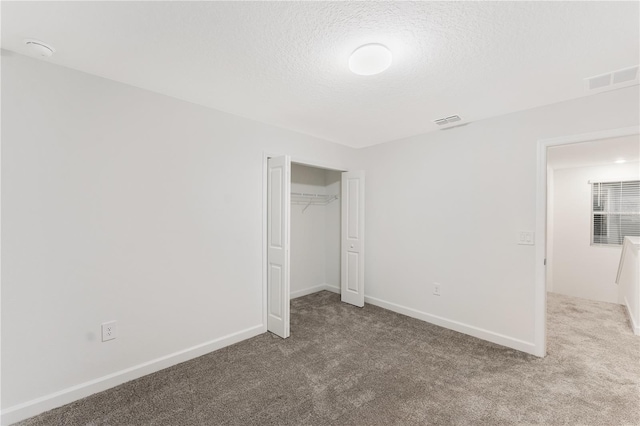 unfurnished bedroom featuring a closet, a textured ceiling, and carpet