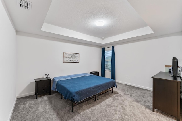 bedroom featuring light colored carpet, a tray ceiling, and a textured ceiling