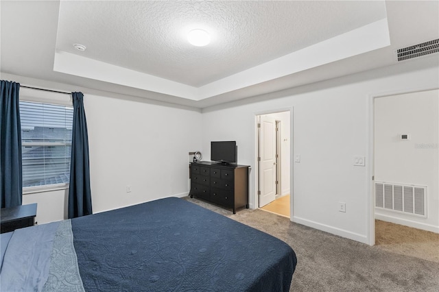 carpeted bedroom featuring a raised ceiling and a textured ceiling