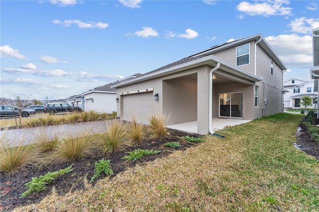 view of side of home with a garage, a patio area, and a lawn