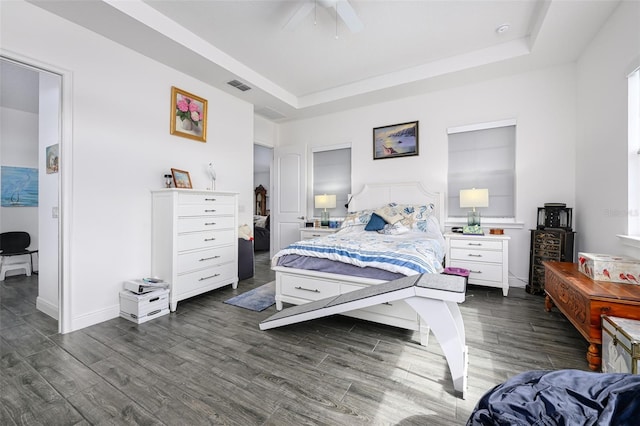 bedroom featuring dark hardwood / wood-style flooring, a tray ceiling, and ceiling fan