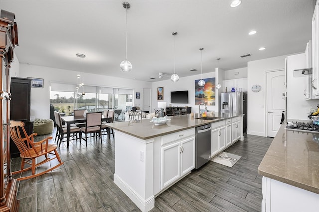 kitchen with stainless steel appliances, an island with sink, hanging light fixtures, and white cabinets