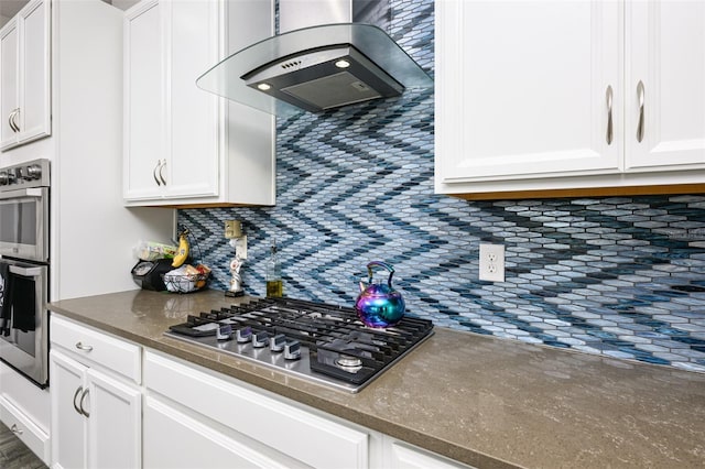 kitchen featuring ventilation hood, white cabinetry, tasteful backsplash, and stainless steel appliances