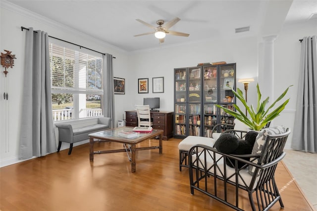 living area with ornate columns, ornamental molding, and light hardwood / wood-style floors