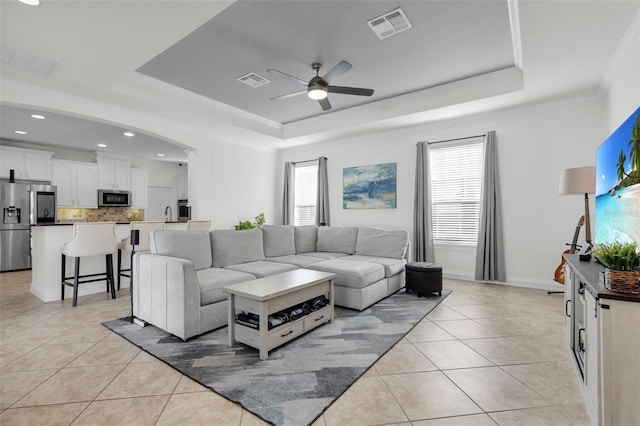 living room featuring light tile patterned flooring, ceiling fan, a healthy amount of sunlight, and a tray ceiling