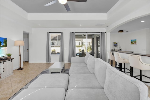 tiled living room with crown molding, a tray ceiling, and ceiling fan