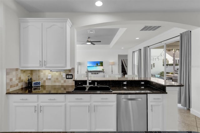 kitchen with white cabinetry, stainless steel dishwasher, dark stone counters, and sink