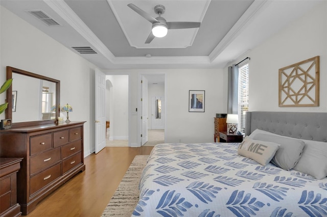 bedroom featuring light hardwood / wood-style floors and a tray ceiling