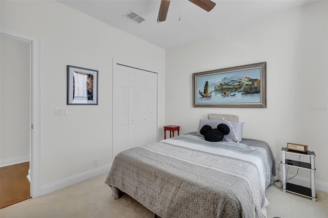 bedroom featuring light colored carpet, ceiling fan, and a closet